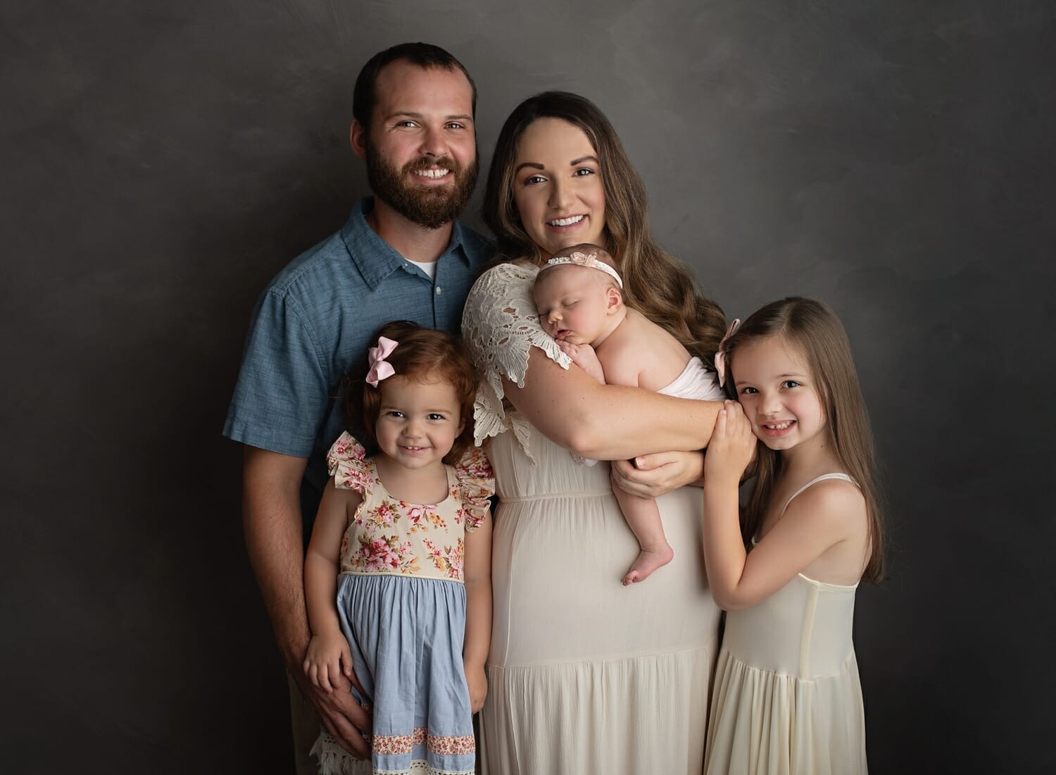 A family with children pose in a studio for New Orleans newborn photography.