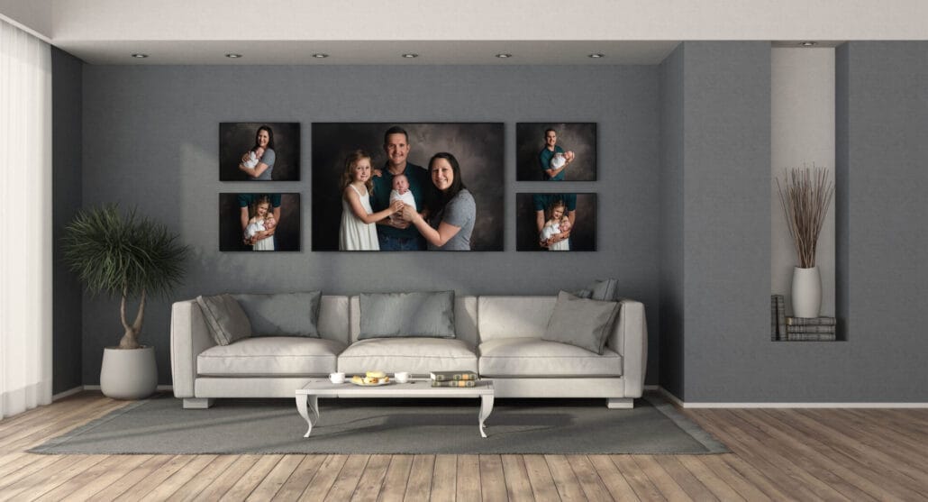 This is a photo of a modern living room with an ivory-colored couch and a wall collection of canvasses of parents and their daughter and newborn with a Baton Rouge newborn photographer. 