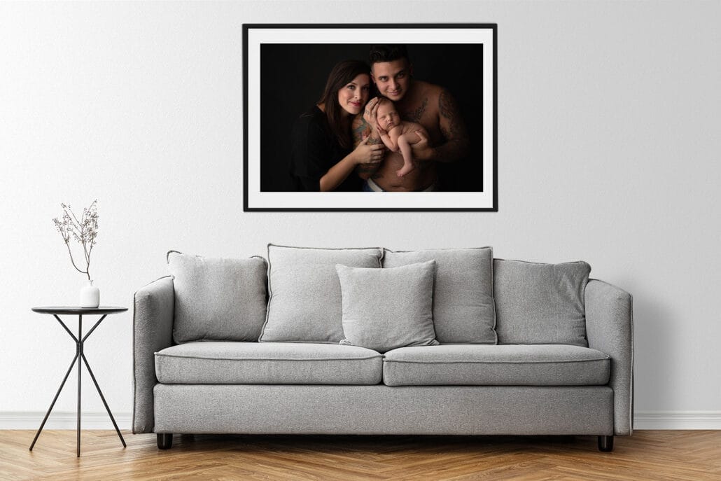 Picture of modern armchair in a minimal decor living room with wall art of parents and newborn boy with Baton Rouge newborn photographer.