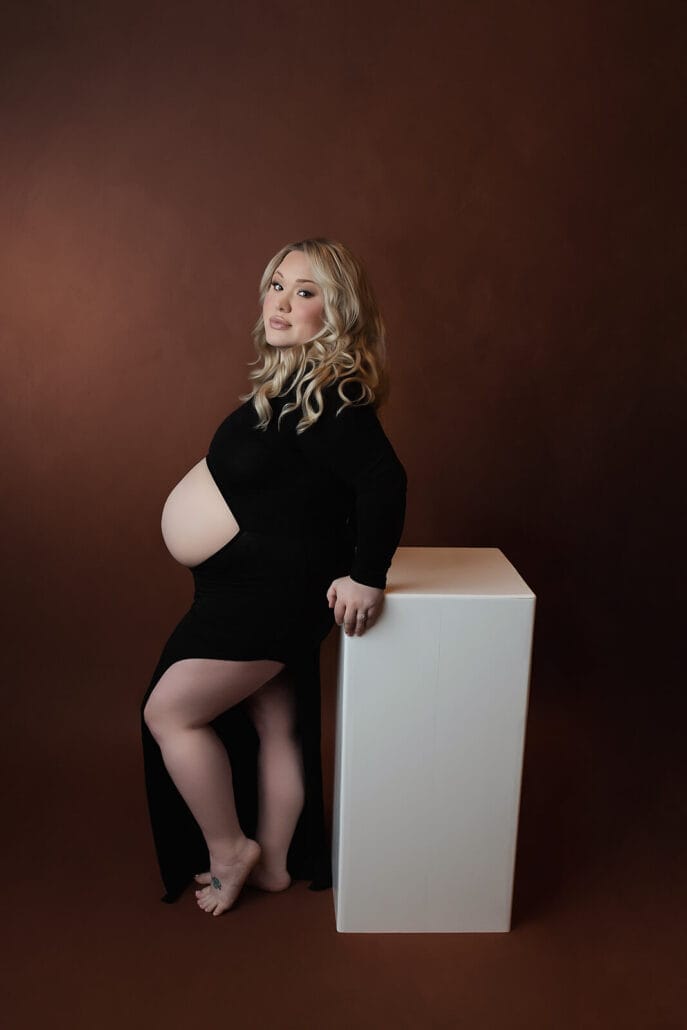 A pregnant mom with black fitted dress with professional hair and makeup thanks to New Orleans massage spa.