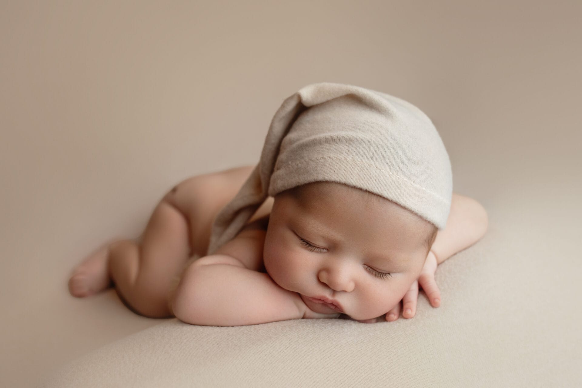 A baby boy in the studio is lying on his tummy with a sleepy hat at the Baton Rouge baby shower venue. 
