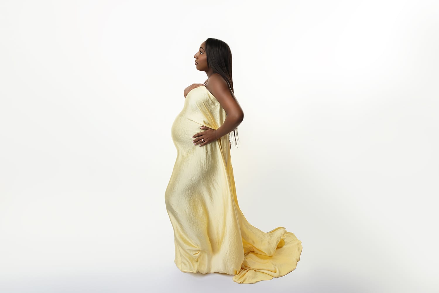 Woman with yellow silk fabric draped over pregnant belly with Lafayette fertility clinic.