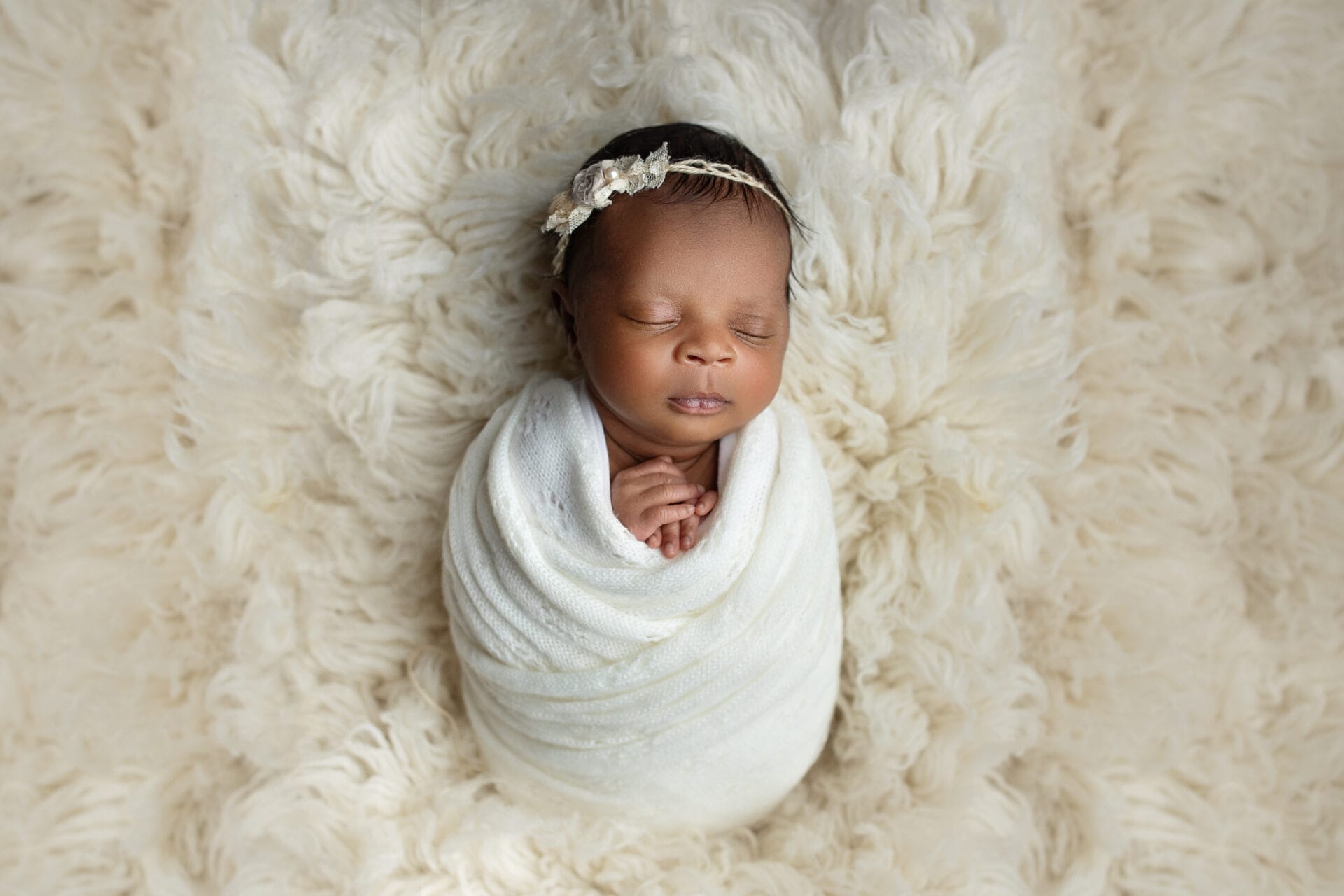 A newborn baby girl swaddled in the studio with an ivory tieback at Lafayette prenatal chiropractor.