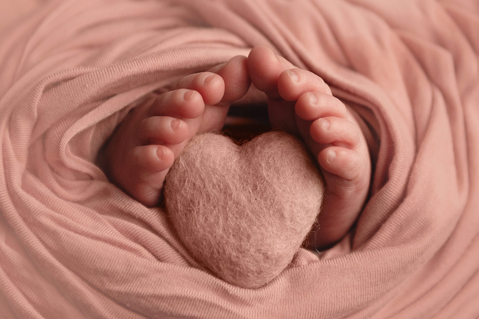 A photo of newborn baby toes surrounding a tiny felted heart with Lafayette top daycare.