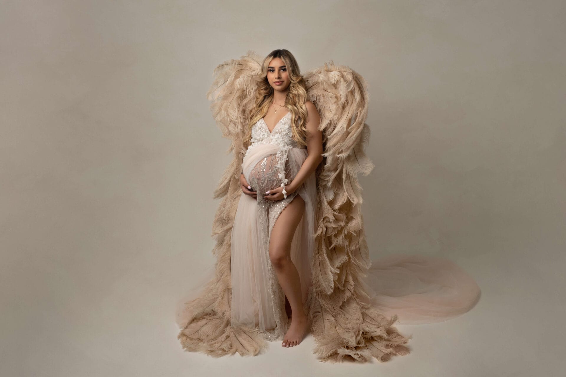 A pregnant woman in the studio with an elegant gown and angel wings at Lafayette water birth location.