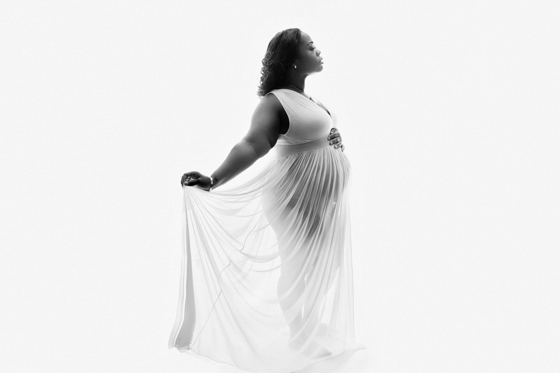 In the studio with a mom-to-be in an elegant white gown as the wind blew her hair, embracing her pregnant belly.